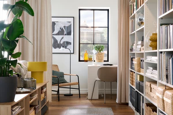 A bright home workspace with a desk by the window, shelving with books and storage boxes, and decorative details in neutral and yellow tones.
