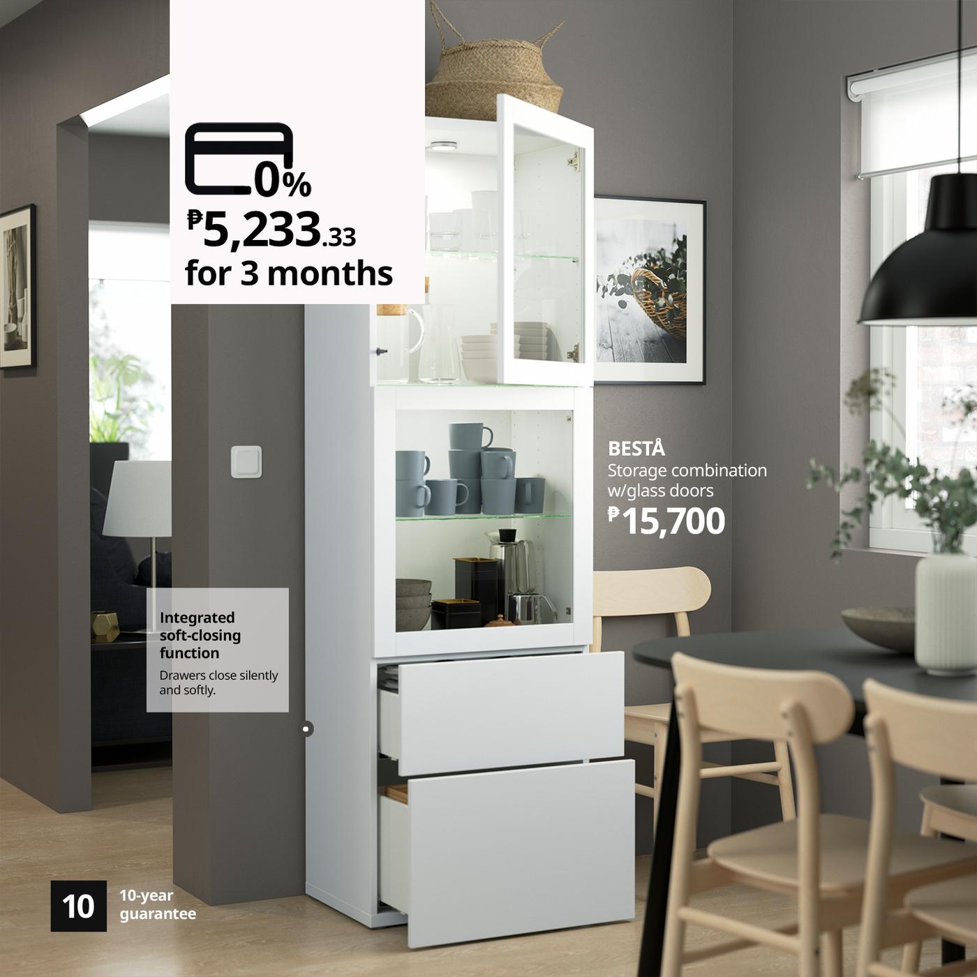 A bright, modern dining room features a white BESTÅ glass-door storage cabinet filled with dishes; ad text highlights ₱15,700 and 0% financing for three months.