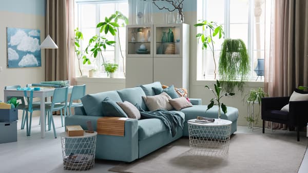 A bright studio with a 3-seat sofa-bed with chaise longue, a white storage combination and a dining area.