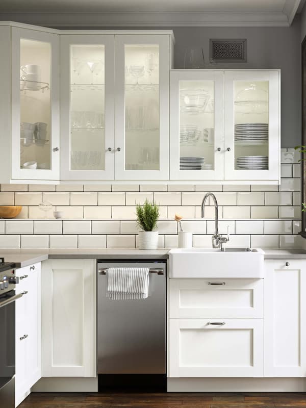 A bright white ENKÖPING kitchen with a subway tile backsplash and a plant sitting on the countertop.