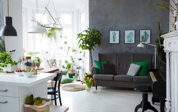 A bright, white kitchen that blends into the living room space where there’s a grey sofa and grey wall.