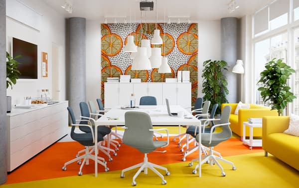 A bright yellow and orange conference room with long white BEKANT table and LÅNGFJÄLL blue and green swivel chairs.
