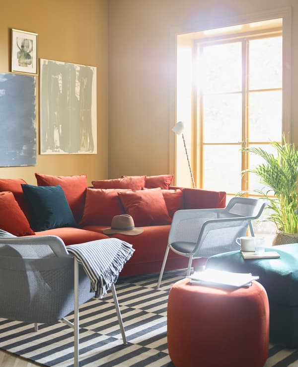 A brightly coloured living room with ochre walls is burnished with a red sofa and armchairs.