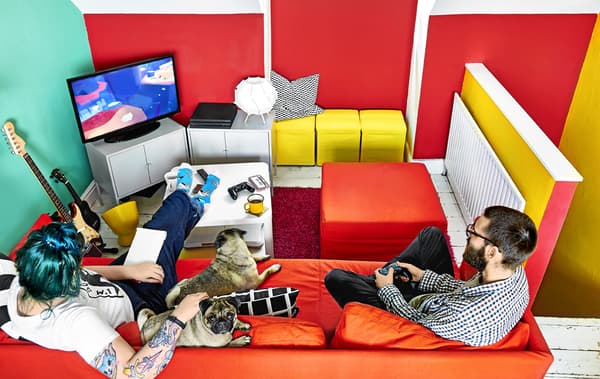 A brightly coloured room with sofa and games console.