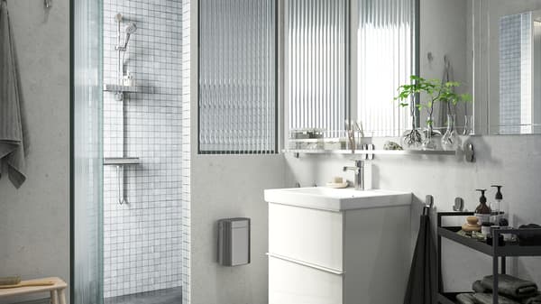 A brightly lit bathroom with a GODMORGON wash-stand, shower with light grey tiles and BROGRUND shower set.