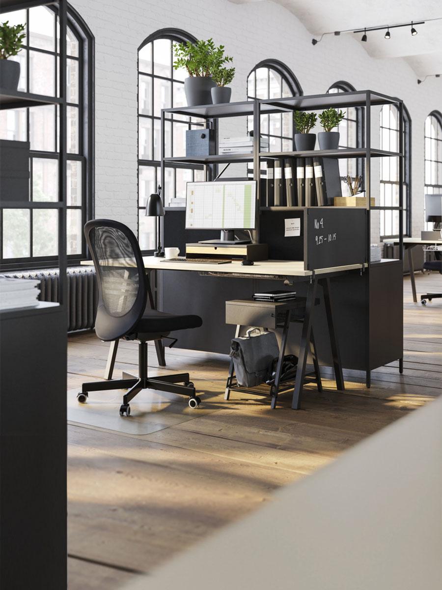 A brightly lit office space featuring a birch table and black office chair.