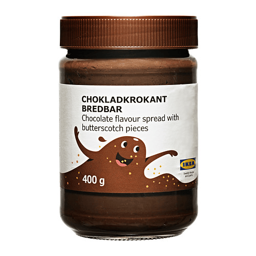 A brown jar of chocolate spread with butterscotch pieces against a white background.