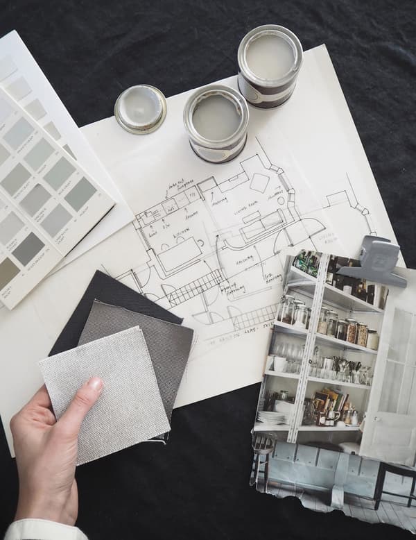 A building elevation drawing and sample pots of paint and fabric.