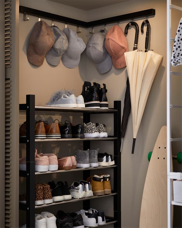 A built-in closet corner where shoe racks in black and stainless steel are stacked to create a high shoe shelf.
