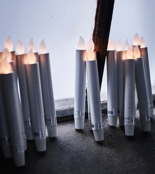A bunch of battery-operated LED candles leaning against a window.