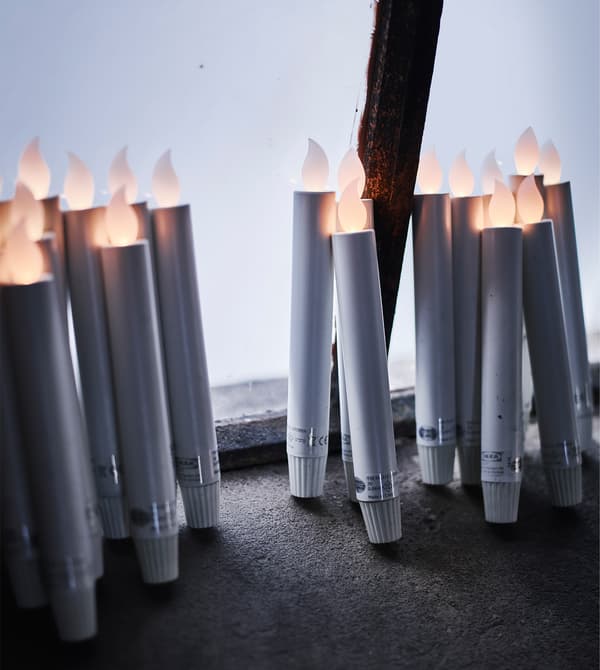 A bunch of battery-operated LED candles leaning against a window.