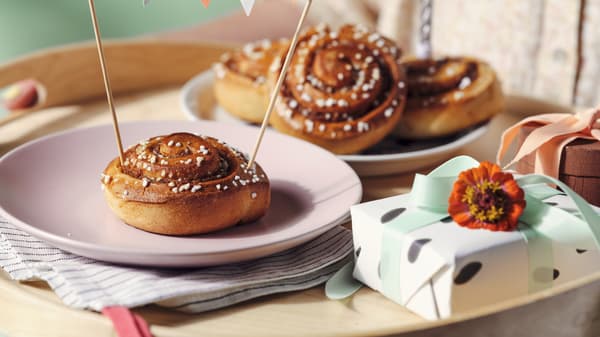 A bunch of cinnamon buns and a present atop a table.