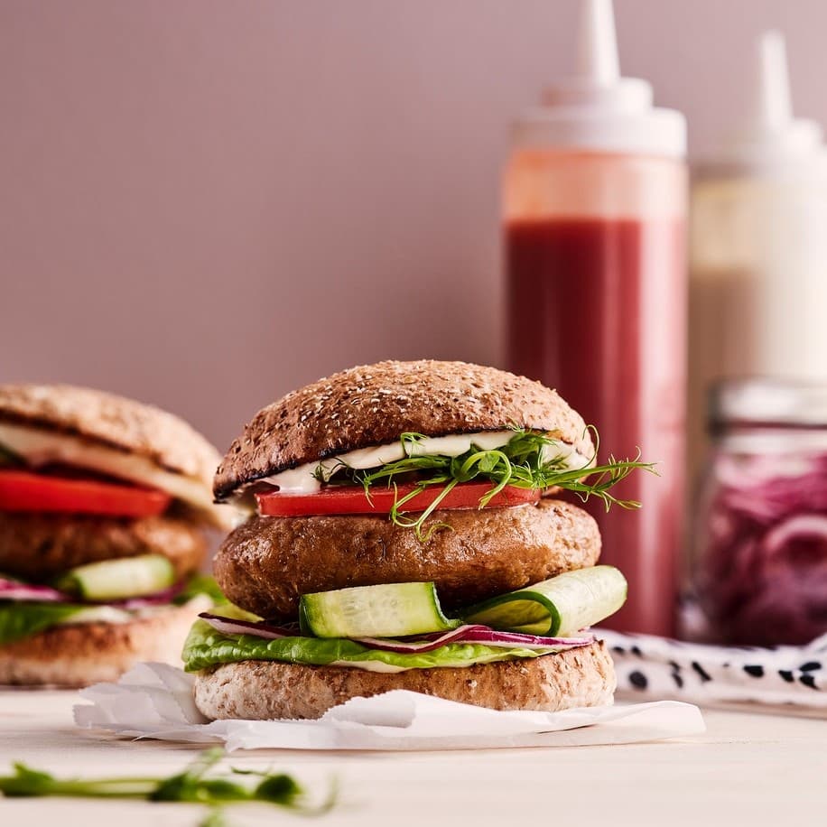 A burger, made from VÄRLDSKLOK plant mince, with cucumber, red onion, lettuce, tomato, sprouts and mayonnaise.