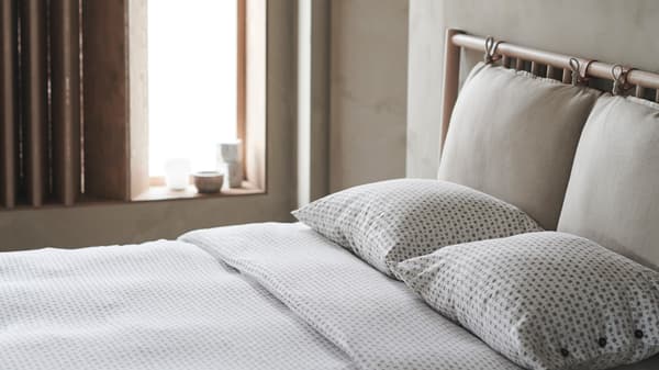 A calm and neutral bedroom in soft daylight, with a double bed styled with VÄGTÅG quilt cover and pillowcases.