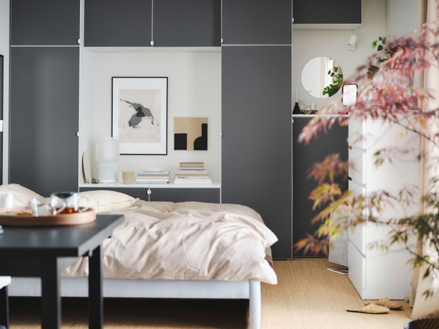 A calm bedroom with a grey GLADSTAD bed, a wooden desk, a dynamic grey wardrobe and round lamps hanging from the ceiling.