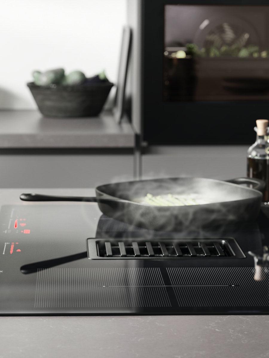 A cast iron VARDAGEN grill pan on an induction hob with integrated fan, in a modern grey kitchen