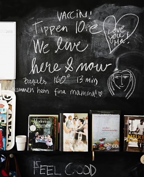 A chalkboard wall with a shelf displaying cookbooks.