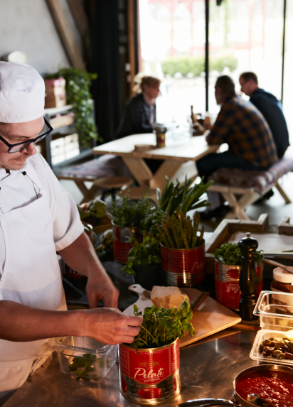 A chef putting toppings on a pizza