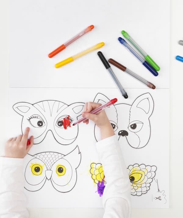 A child colouring in animal-shaped masks in a book.