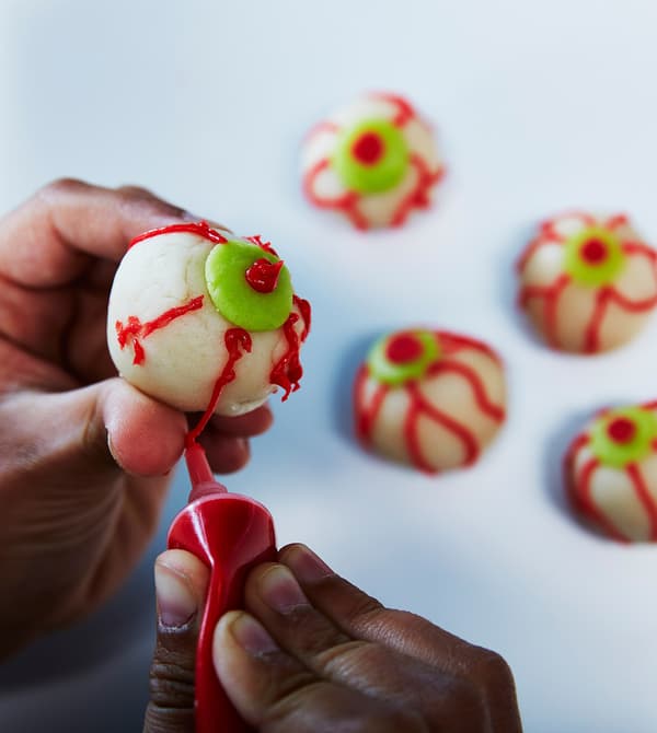 A child decorates eyeball treats for Halloween.