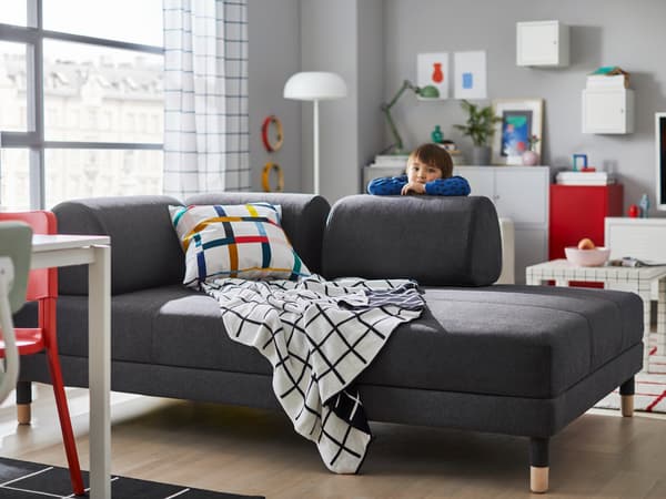 A child hiding behind the modern gray FLOTTEBO sleeper sofa.