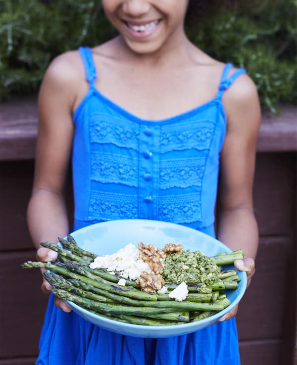 A child holding a plate of vegetarian food.