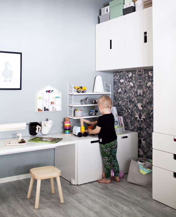 A child playing in a neutral colour-schemed bedroom with white furniture.
