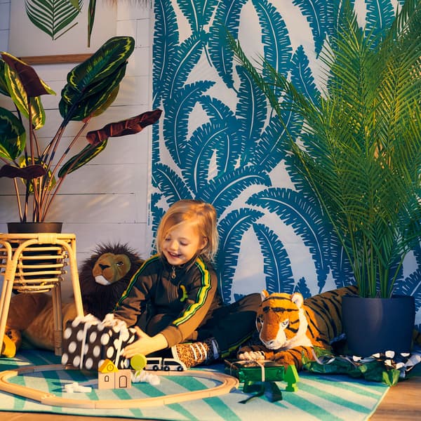 A child playing with stuffed animals and a toy train set on the floor.