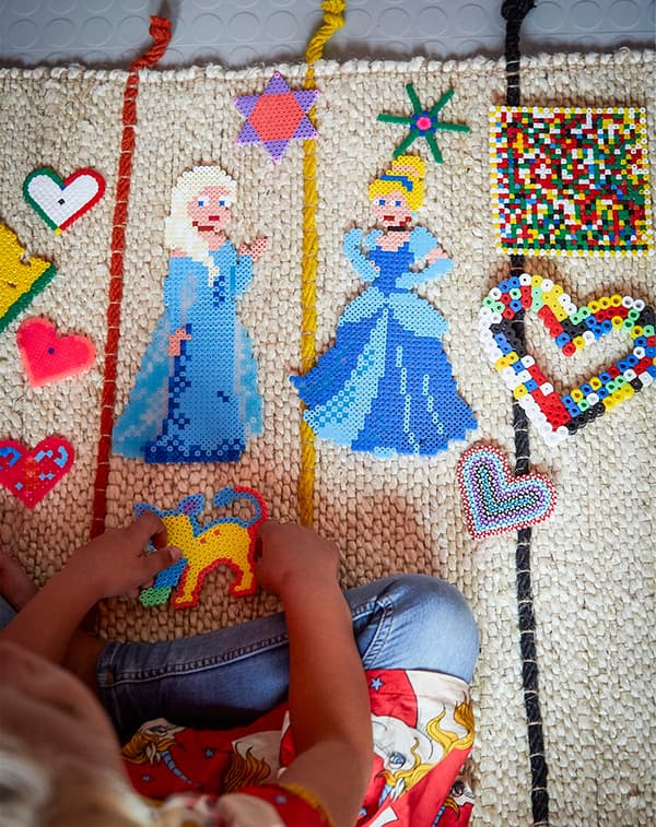 A child playing with toys on a colourful rug.