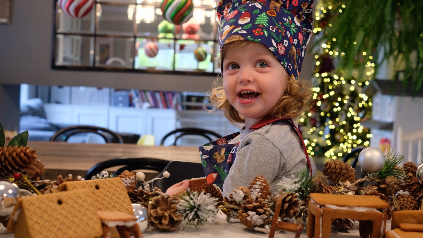 A child sitting in a room surrounded by Christmas decorations