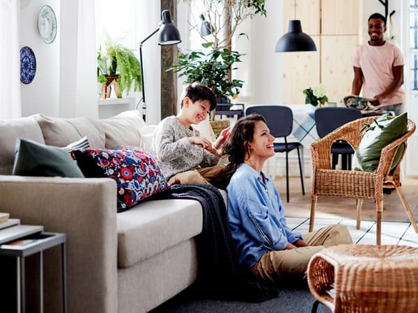 A child sitting on a FRIHETEN sleeped playing with a woman's hair. Rattan chairs in the room with them.