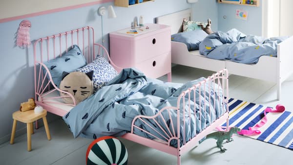 A children's bedroom with a light pink MINNEN extendable bed and a white bed made with blue VÄNKRETS and BARNDRÖM bedding.