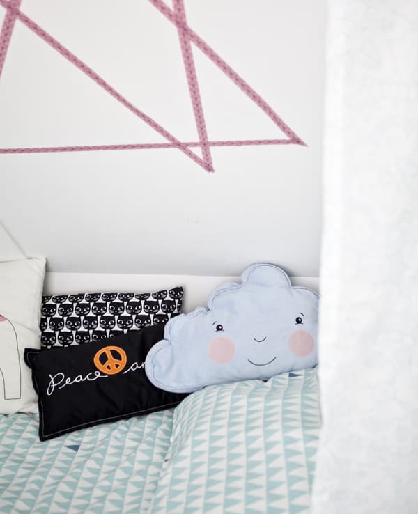A child's bed decorated with colourful cushions.