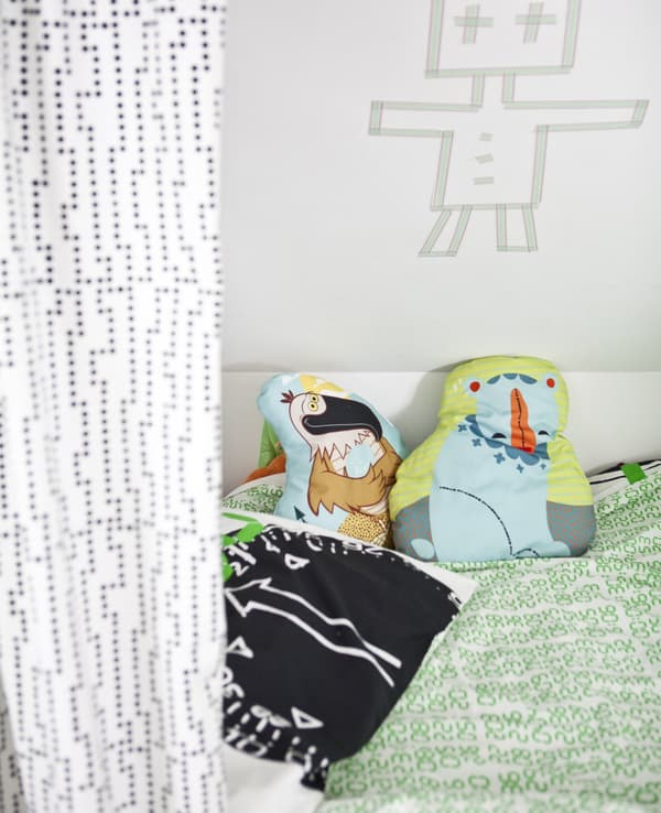 A child's bed with colourful bedding and cushions.