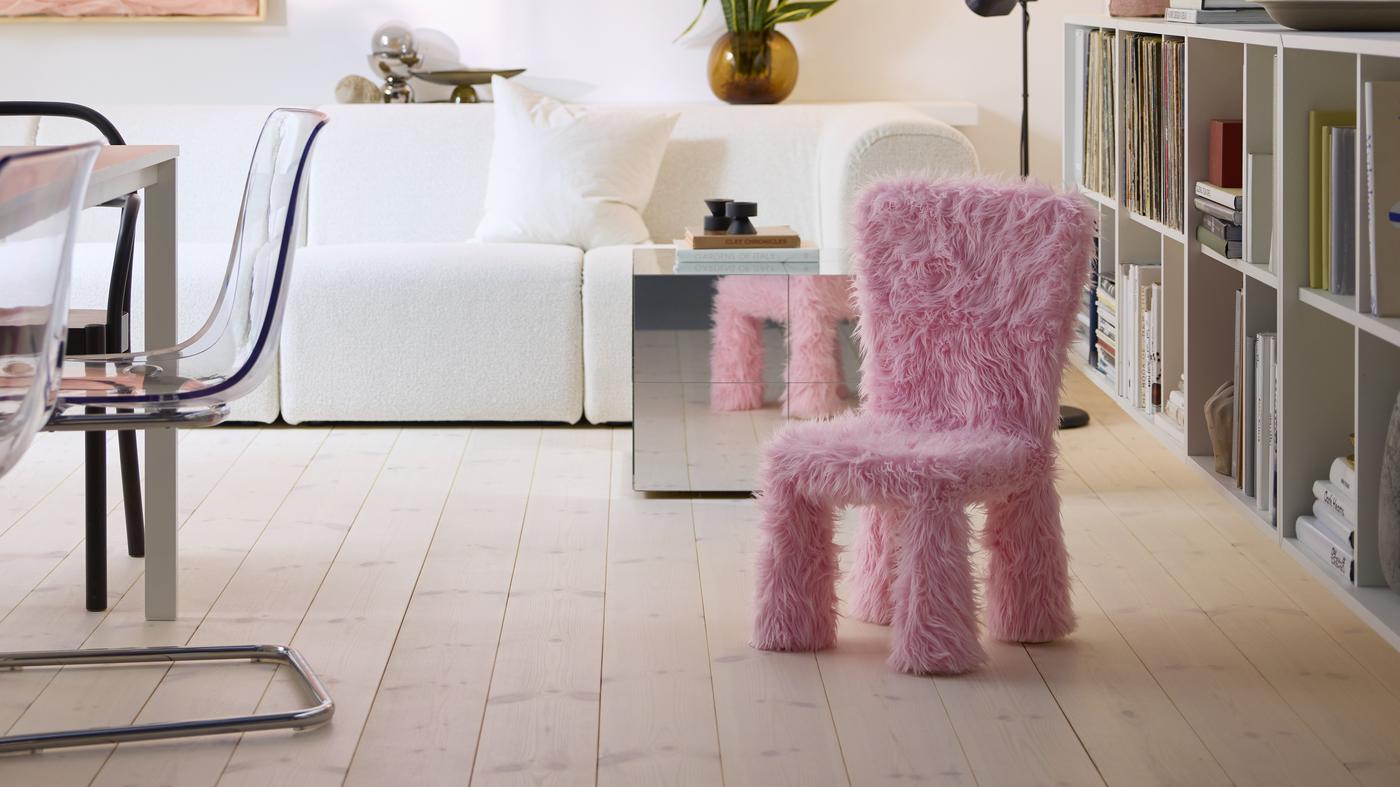 A child’s chair in a GRESIMOJS chair cover in pink faux fur is in a bright and modern living room, by a mirrored side table.