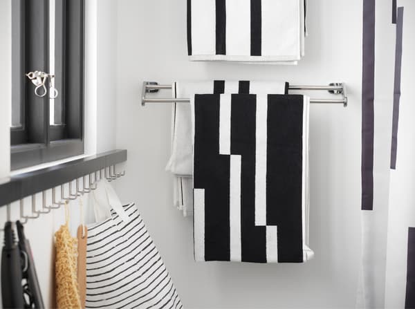 A chrome-plated towel rail where black/white striped towels hang. It's mounted next to the shower.