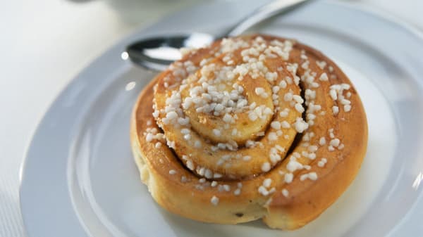 a cinnamonbun on a plate with a spoon