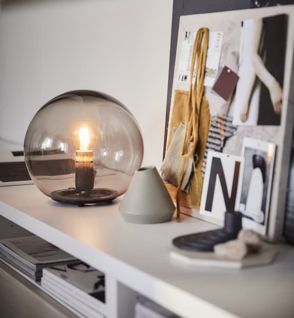 A circular table lamp on a table surface with decorations on it.