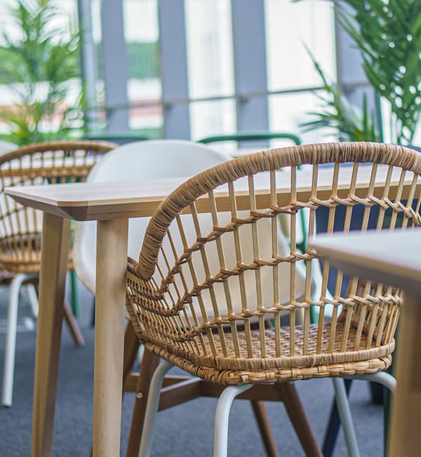 A close-up featuring a weaved and white chair tucked in a wooden table.