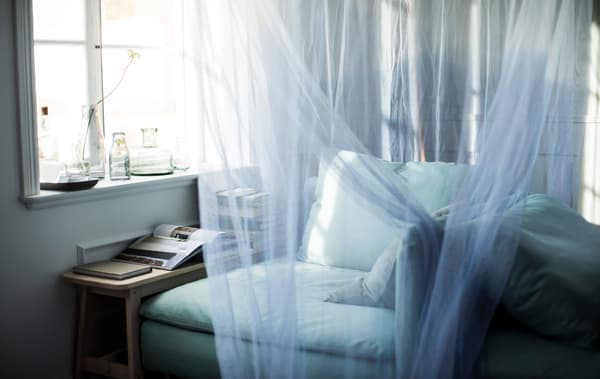 A close-up image of a cozy corner with an IKEA SÖDERHAMN corner section draped in a canopy.