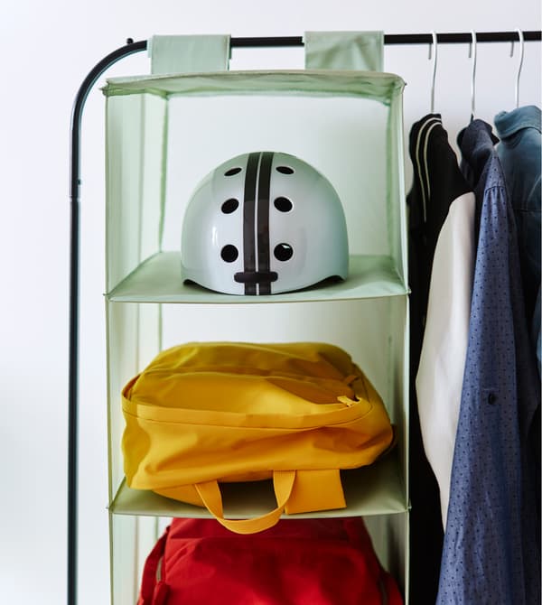 A close-up image of a hanging organizer filled with a helmet, bags and sweaters.