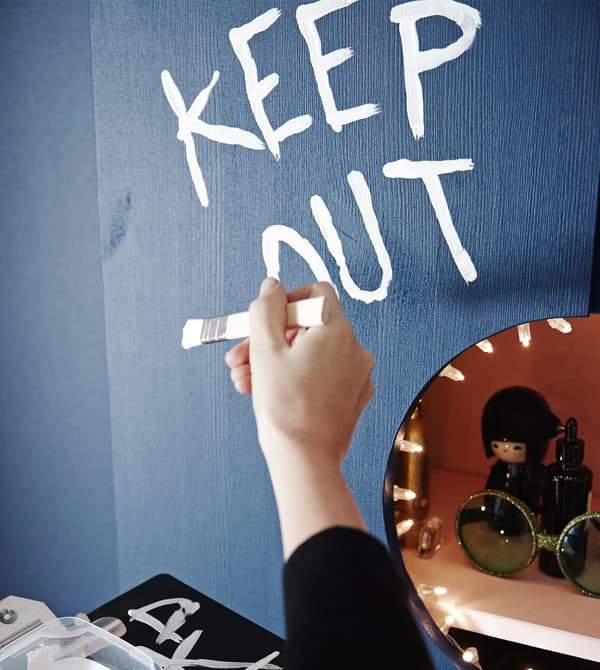A close-up image of an interior designer painting “Keep Out” on the vanity cabinet.