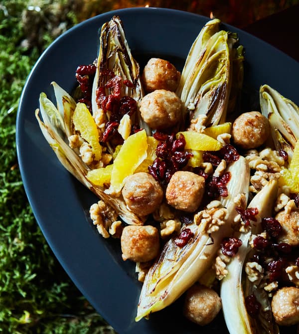 A close-up image of chicken meatballs with endives and orange.