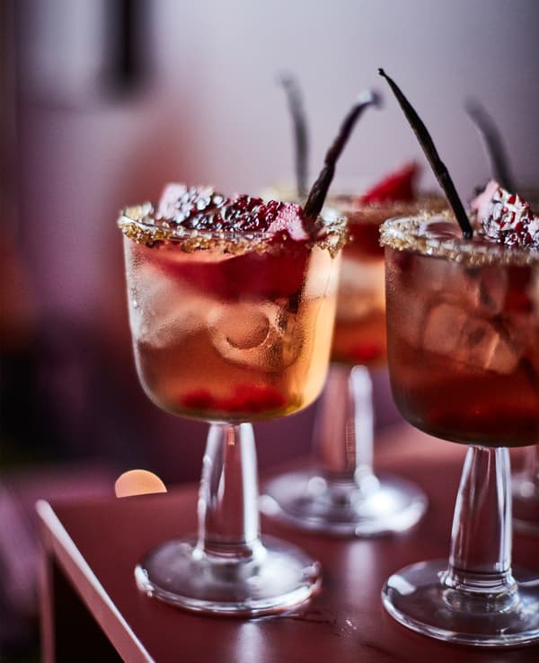 A close-up image of pear ginger spritzes garnished with pomegranates and vanilla beans.
