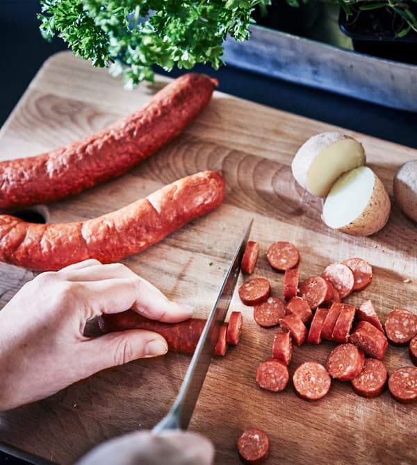 A close-up image of sausages being sliced on a chopping board.