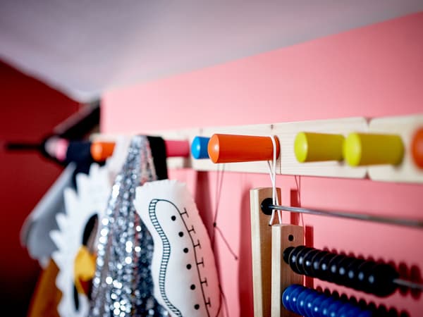  A close-up image of toys and costumes hung from colorful hooks on the wall.