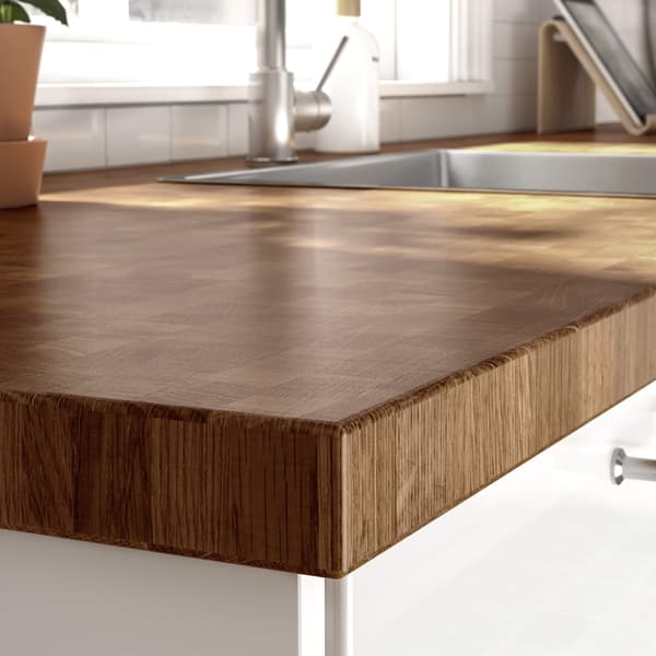 A close-up of a countertop on top of black base cabinets and drawers by a marble wall panel.