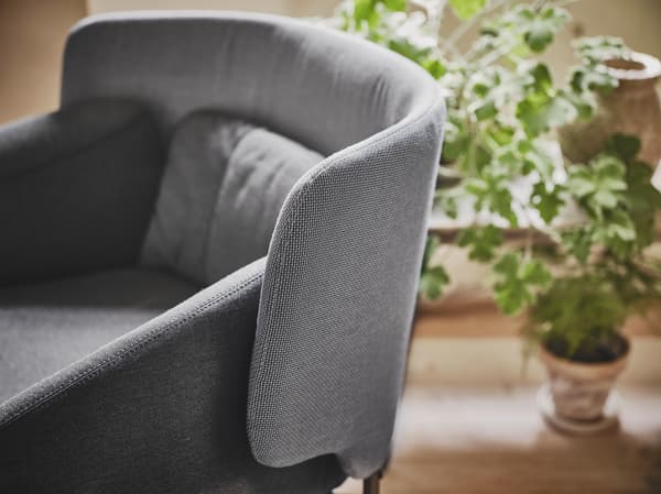 A close-up of a gray low back BINGSTA armchair featuring curved armrests and an enclosing back panel.