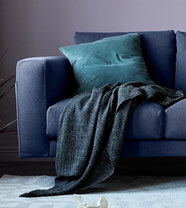 A close up of a grey sofa with a throw and cushion.