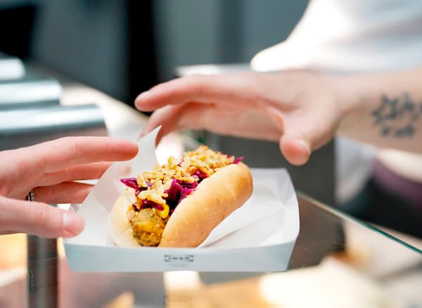 A close-up of a hand reaching for the IKEA veggie hot dog.